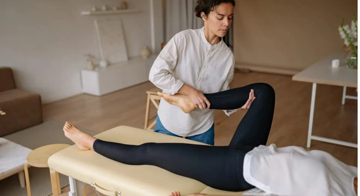Physiotherapist guiding an adult through a seated knee extension exercise